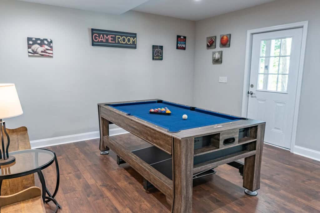 Game room with a rustic pool table, colorful decor, and a door leading to an outdoor area.