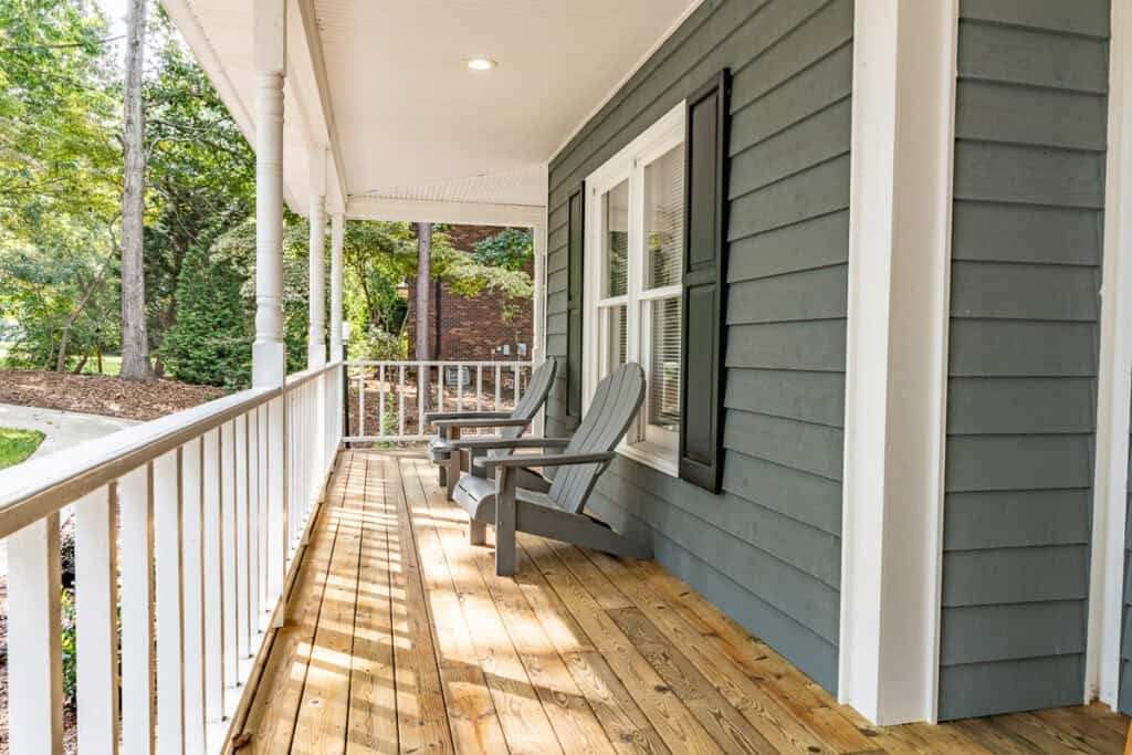A charming covered porch featuring two Adirondack chairs, perfect for enjoying serene views of the property.