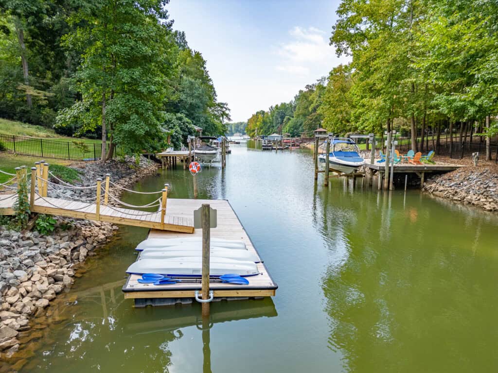 A peaceful lakeside dock with space for kayaks and a small boat. Surrounded by lush greenery, this area is perfect for relaxation or water activities.