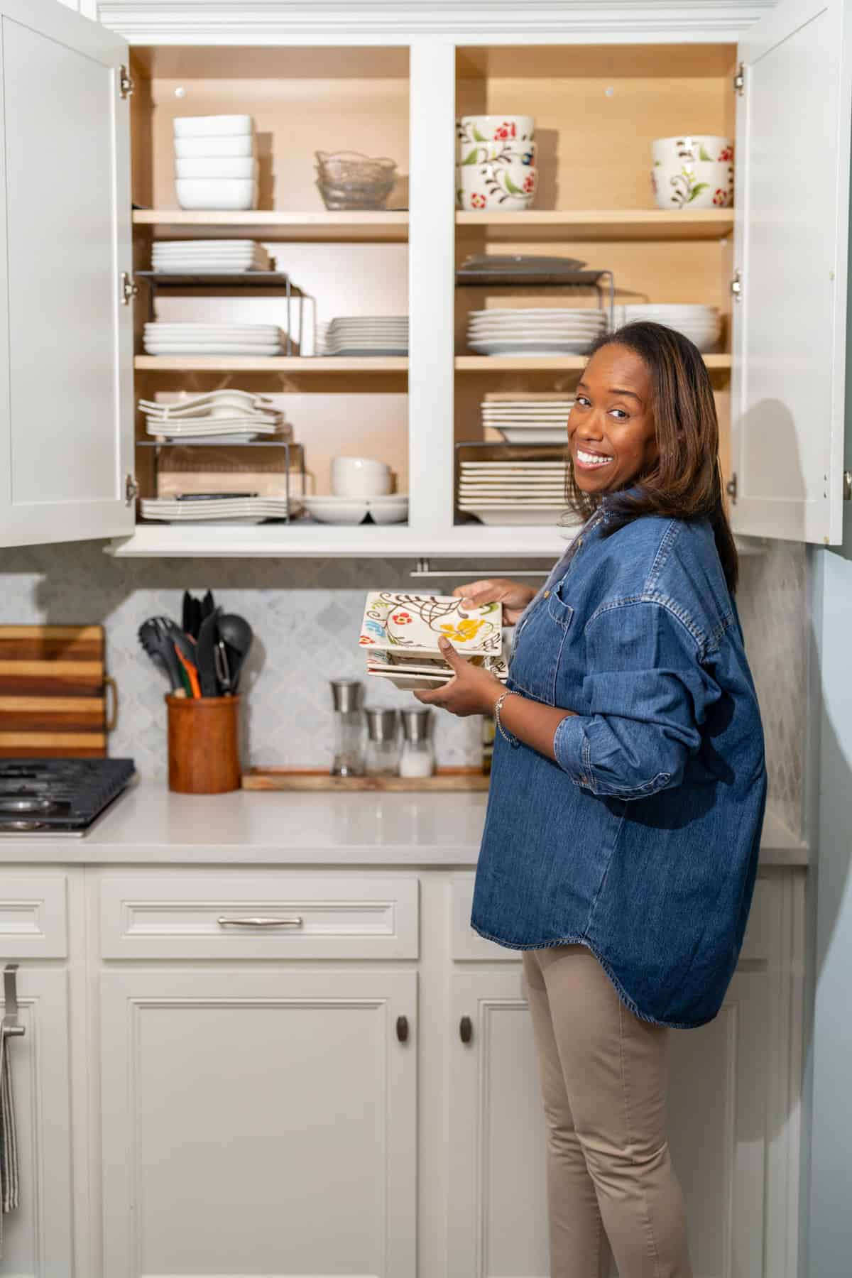a woman holding plates in a kitchen